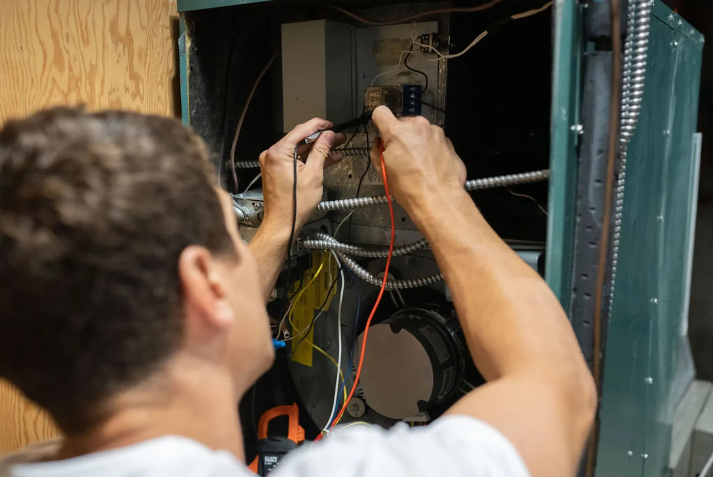 Reid Pro technician testing a furnace's controls with a meter