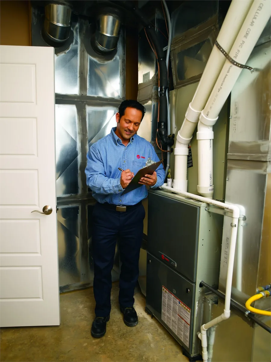 Technician checking a Trane high-efficiency furnace with PVC venting