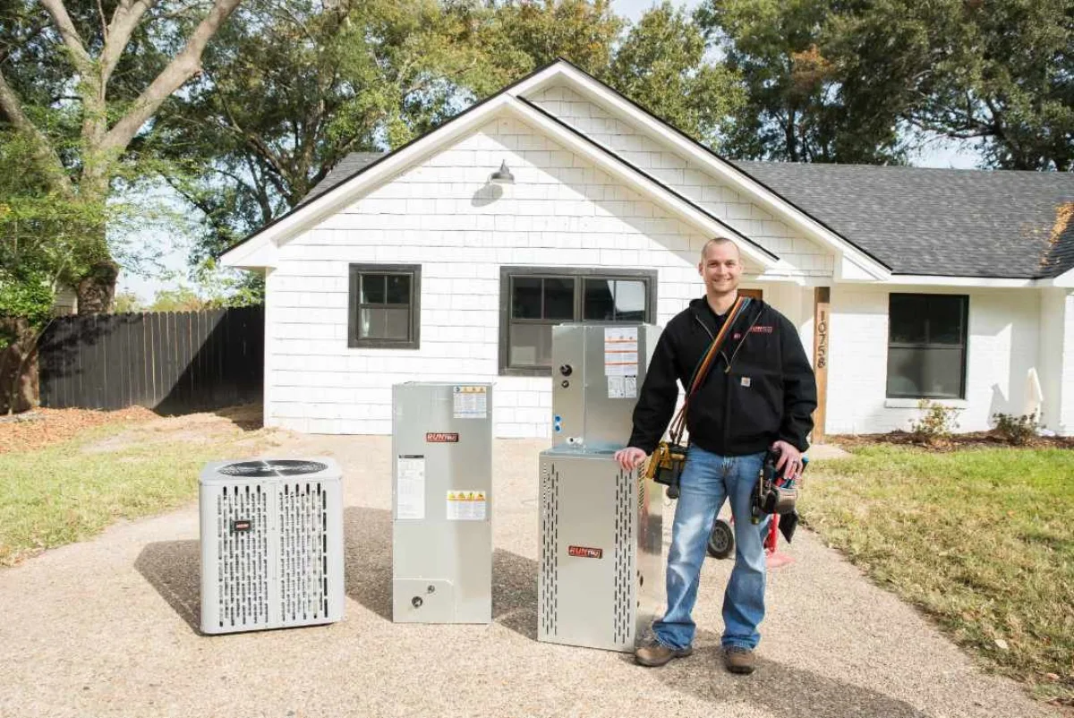Technician with a Trane furnace, air handler, and AC unit outside a home