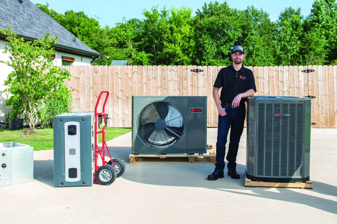 Technician moving a Trane heat pump into place at a home