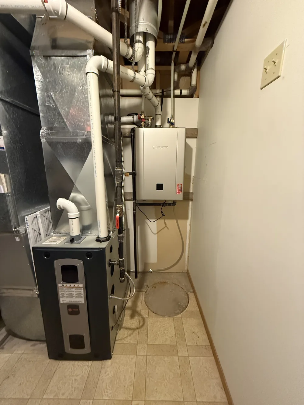 New wall-mounted tankless water heater installed by Reid Pro beside a new Trane furnace